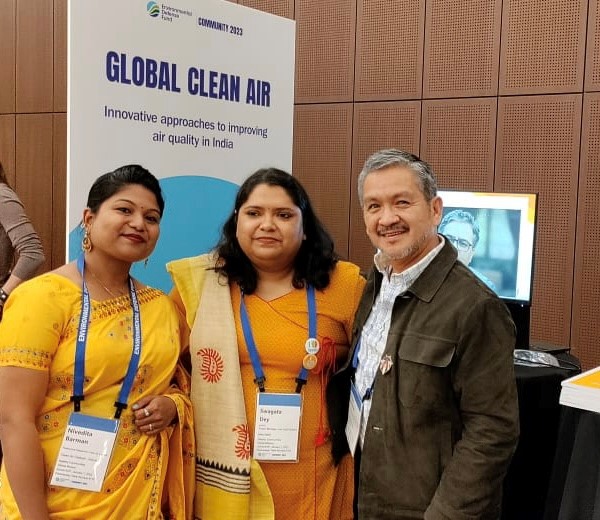 Two women and one man stand in front of a banner reading “Global Clean Air”