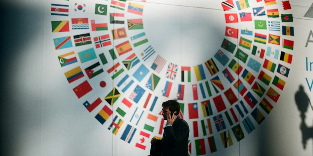Man on the phone front of flags of the world